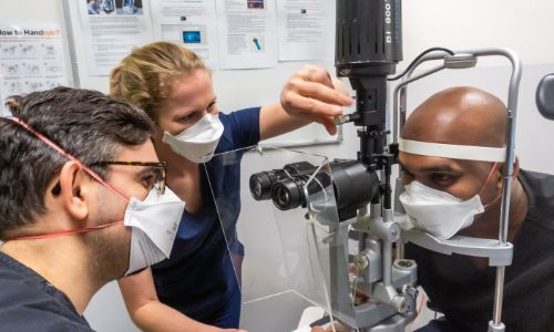 Two eye doctors examining a patient's eyes through a microscope