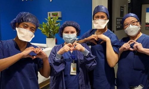 Four nurses in nursing scrubs, holding their hands up in a heart shape